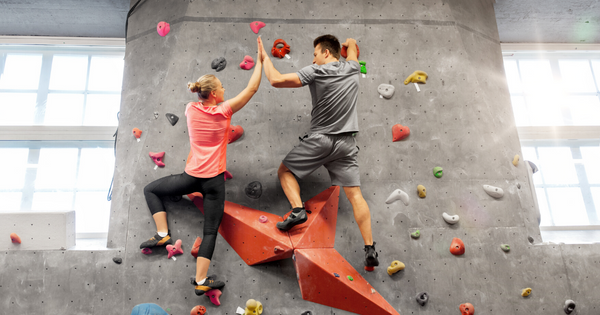 Family members high-five at the top of a rock wall