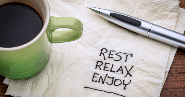 Coffee cup on napkin. Written on napkin: Rest, relax, enjoy.