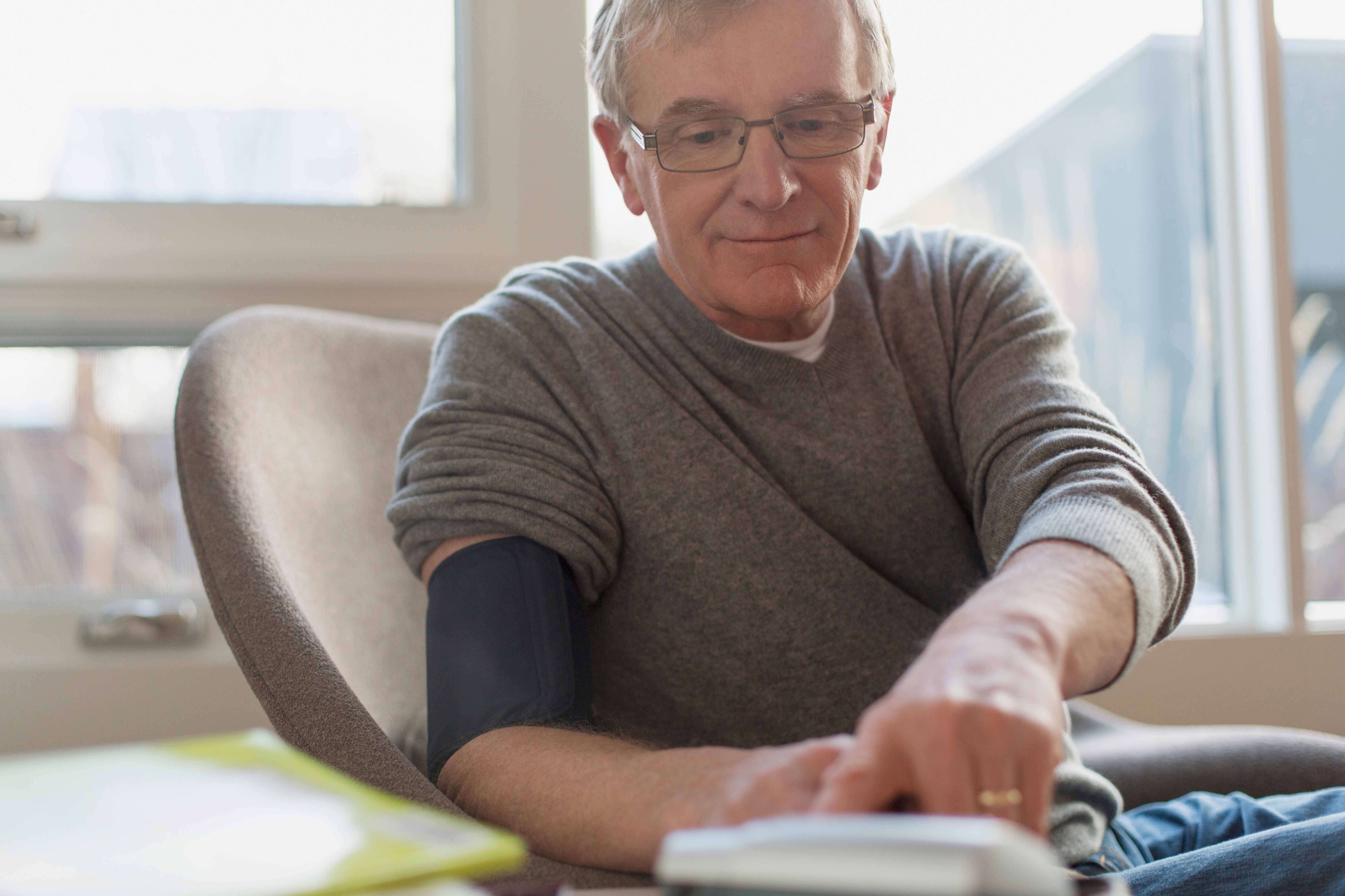 An elderly man testing his blood pressure at home