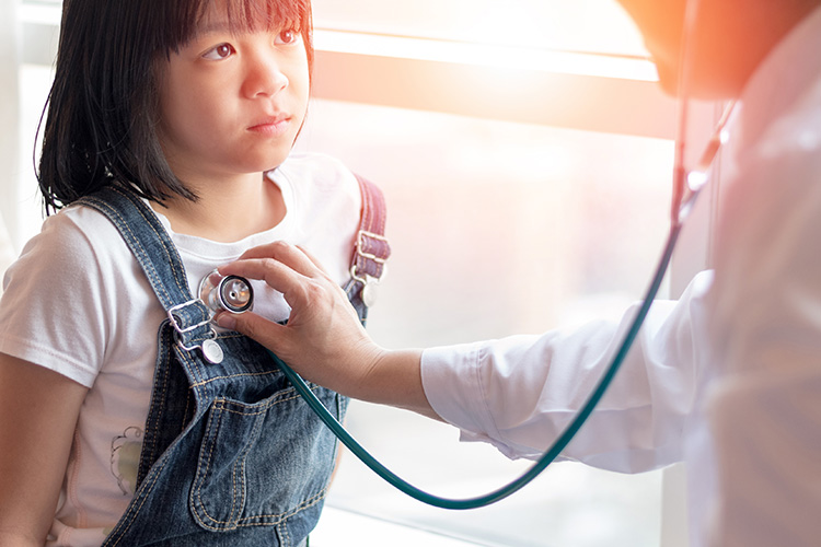 Provider listening to young patient's vitals with stethoscope.